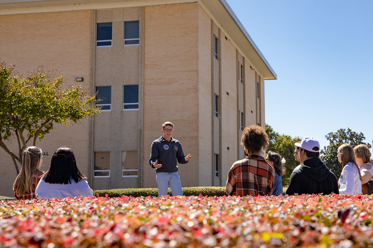 A Hawkseeker tour guide stands in front of a group of students on a  campus tour.